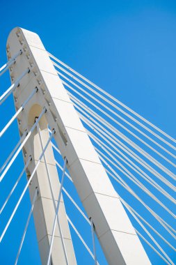 Mavi gökyüzüne karşı destek kabloları olan bir köprü sütununun soyut görüntüsü  