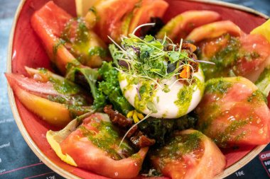 Pesto soslu sulu domateslerle dolu Burrata peynirli salata resmi. 