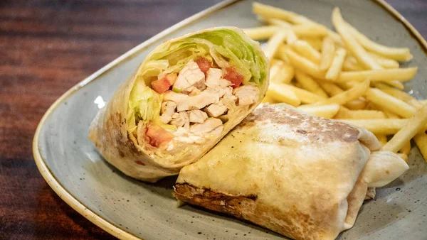 一个新鲜准备的鸡肉玉米饼包在沙拉里 与法式薯条一起就餐的精美图像 — 图库照片