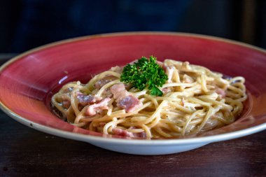 Kırmızı kasede servis edilen taze bir spagetti carbonara..