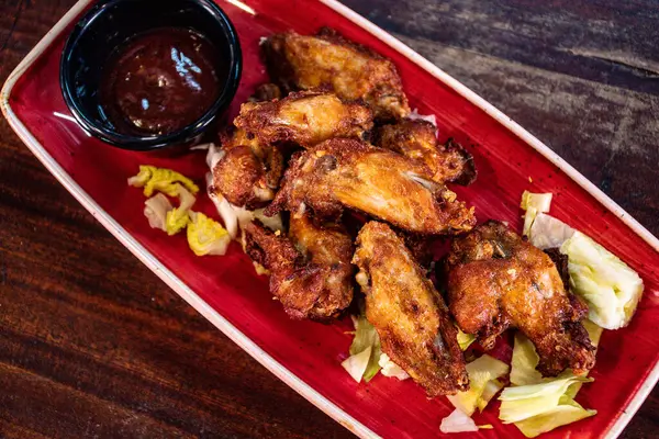 a birds eye view of a plate fried chicken wings served with barbecue sauce.