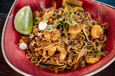 Kırmızı kasede servis edilen Tayland usulü karideslerin yakın plan görüntüsü..