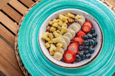 Tahta bir masada taze meyve ve böğürtlenli taze acai dondurması üzerine yakın plan bir görüntü. 