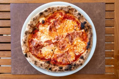 Bir tabak taze İtalyan jambonlu ve peynirli pizzanın üzerine kuş bakışı bir bakış. 