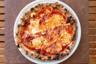 Bir tabak taze İtalyan jambonlu ve peynirli pizzanın üzerine kuş bakışı bir bakış açısı.