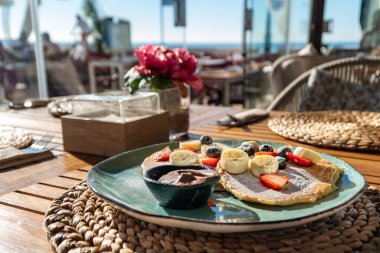 Akdeniz sahilindeki bir barda taze meyve ve çikolatayla kaplı taze yapılmış krep tabağının yakın plan görüntüsü.