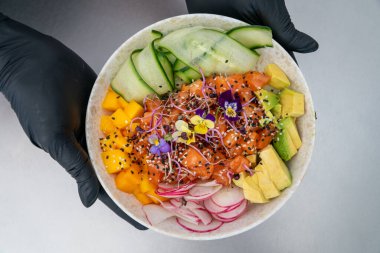 Yeni hazırlanmış somon kabını sunan şefe bakan bir resim. 