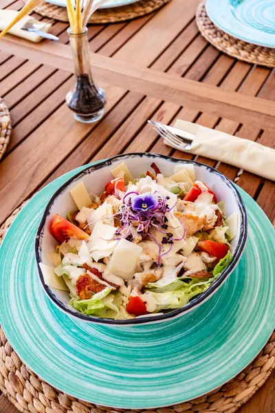 Tahta bir masada taze yapılmış Akdeniz tavuğu Sezar salatası manzarası. 