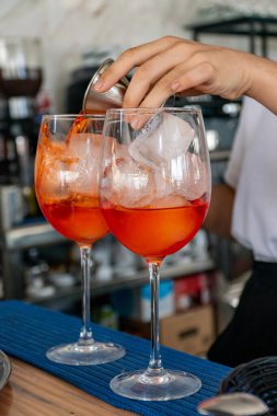 Akdeniz barında bir çift İtalyan Aperol Spritz kokteyli hazırlayan bir barmen. 