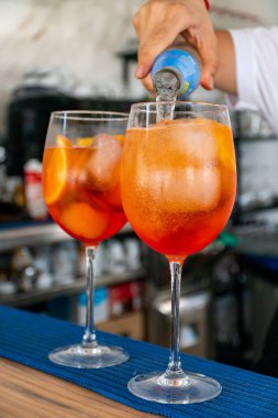 Bir barmen bir çift İtalyan Aperol Spretz kokteylini soda ile bitiriyor. 