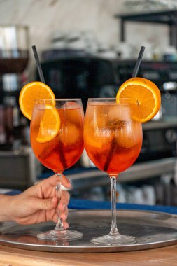 Yeni hazırlanmış İtalyan Aperol Spretz kokteyllerini sunan bir barmen.