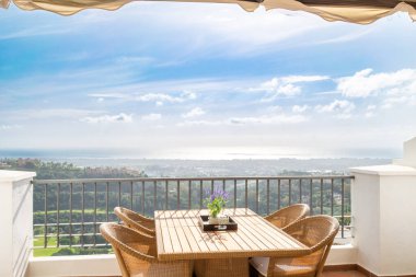 a dining table on a luxury apartment terrace with views overlooking the town of Marbella clipart