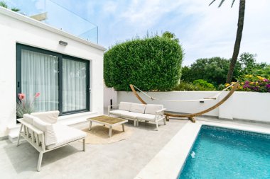 Lüks bir Akdeniz gayrimenkulünde havuz kenarındaki kanepeler ve bir hamak. 