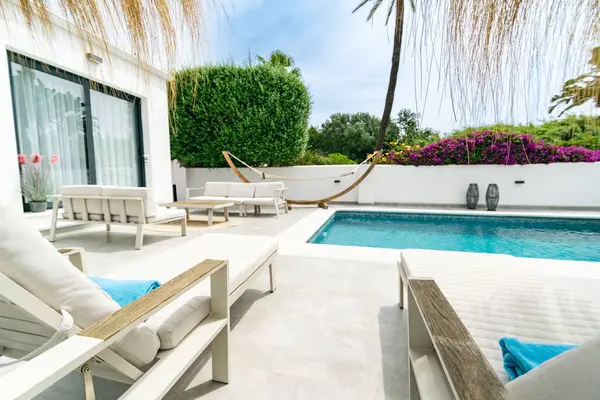 Akdeniz 'de bir villada sandalye ve güneşlikle dolu bir havuz kenarı görüntüsü. 