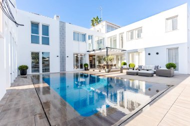 Akdeniz malikanesinde bahçe mobilyalarıyla çevrili lüks bir sonsuzluk yüzme havuzu.