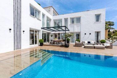 Lüks bir Akdeniz tatil konağında bahçe mobilyaları olan bir havuz kenarı görüntüsü. 