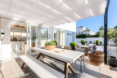 Akdeniz villasında lüks ahşap mobilyaların yanında açık hava yemek masası.