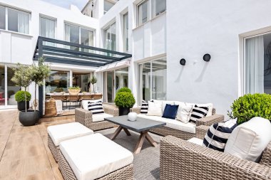 Lüks Akdeniz malikanesinde çeşitli sandalye ve masaların güneşli bahçe görüntüsü