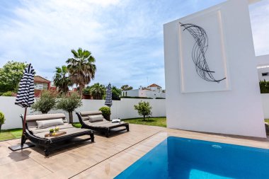 Akdeniz malikanesinde sonsuz bir yüzme havuzunun yanında bir çift lüks güneş dinlenme yeri. 