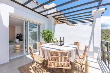 Lüks apartman terasında ahşap sandalyeli yuvarlak bir yemek masası resmi. 