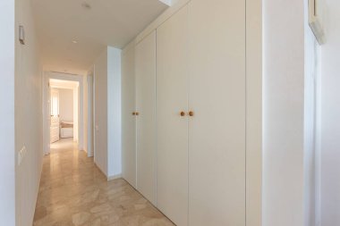 Tatil dairesinin yatak odasındaki beyaz kostümlerin resmi. 