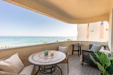 Akdeniz manzaralı balkon terasında küçük bir masa ve sandalyelerin yakın çekimi.