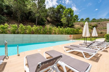 Akdeniz toplumunda özel bir yüzme havuzu etrafındaki güneşli yatakların görüntüsü 