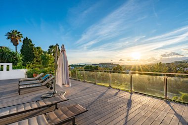 Güneş batarken lüks balkon terasından güneşli yataklara bakan golf sahasına bakan bir manzara.