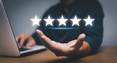 hand of customer or client holding the stars to complete five stars. with copy space. giving a five star rating. Service rating, satisfaction concept.