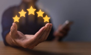 hand of customer or client holding the stars to complete five stars. with copy space. giving a five star rating. Service rating, satisfaction concept.