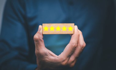 Müşteri hizmetleri en iyi iş derecelendirme deneyimi. Memnuniyet araştırması konsepti. Bir iş adamının eli tahta kübün üzerinde gülen bir yüz seçer. 5 Yıldız Memnuniyeti.