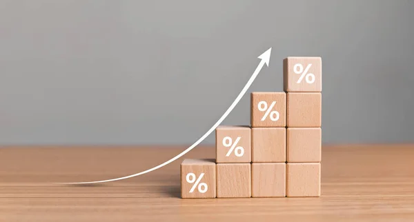 Interest rate financial and mortgage rates concept. Wooden blocks with Icon percentage symbol and arrow pointing up. The economy is improving.