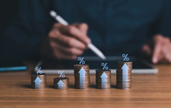 Interest rate increase and dividend concept, Businessman is calculating income and return, interest rate up, coins with up arrow and percentage symbol banking increase interest.