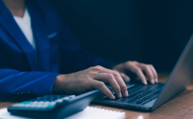 İş adamı hesap makinesi ve not defteriyle dizüstü bilgisayarda daktilo kullanıyor. Ofis işleri, mali yönetim, veri girişi ve modern işletmeler. Uzak çalışma, dijital iletişim.