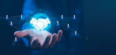 Küresel iş ortaklığı ve ağ. İnsan simgeleri, iş birliği, güven, iletişim ağlarıyla dijital bir dünya haritasına bağlı parlak bir el sıkışma simgesi tutuyor.