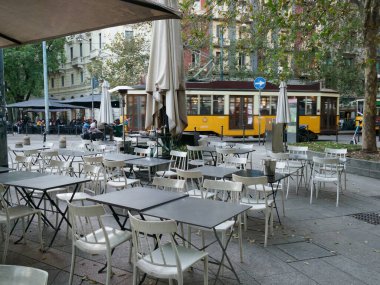 Tables and yellow tram at Milan, Lombardy, Italy clipart