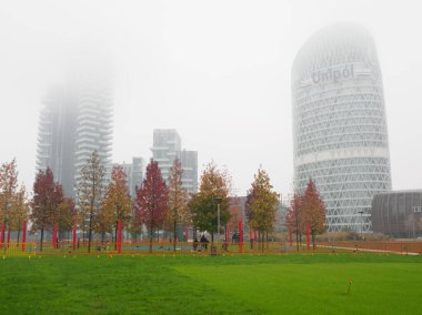 Modern buildings at Porta Nuova, Milan, Lombardy, Italy, and Biblioteca degli Alberi park in a November misty morning clipart