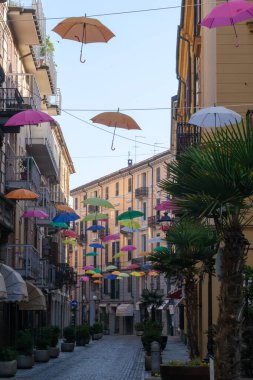 İtalya, Piedmont, Alessandria 'daki San Lorenzo boyunca renkli şemsiyeli tarihi binalar.