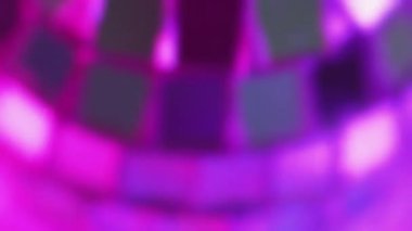 Disko partisi. Gece kulübü ekipmanları. Modern şenlikli dekoratif bulanık gümüş parlak yuvarlak müzik aynası topu büyüleyici atmosferde neon renkli ışıkta dönüyor..