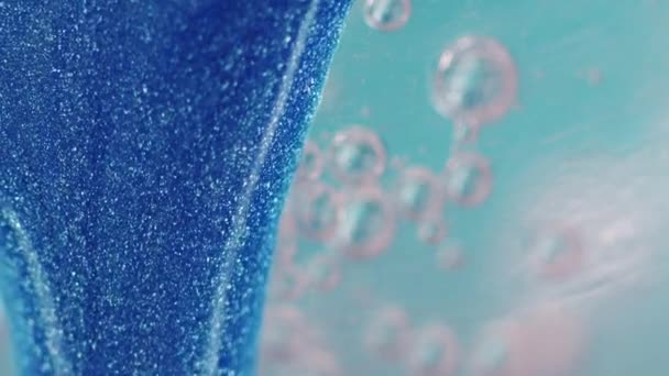 グリッターフルードリップ ペイントフロー 青い色の輝く金属粒子のテクスチャーのインク動きはコピースペースが付いている芸術の抽象的な背景を泡にします — ストック動画