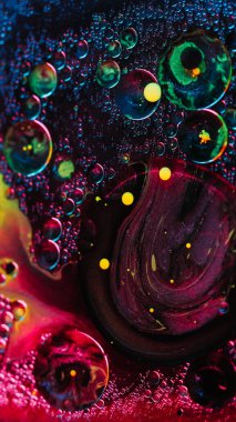 Soyut arkaplan. Boya baloncukları. Renkli yağ suyu. Mor sarı parıldayan daireler hipnotik yaratıcı sıvı sanatta neon parlaklığında hareket eder..