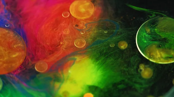 Color mist. Ink water bubble. Defocused bright neon yellow pink green smoke veil texture oil paint drop floating on dark black abstract art background.