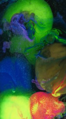 Mürekkep damlası. Yağ kabarcıkları. Odaklanmamış neon yeşil, pembe, simli, şeffaf boya karışımı koyu siyah sanat soyut arka planda yüzüyor..