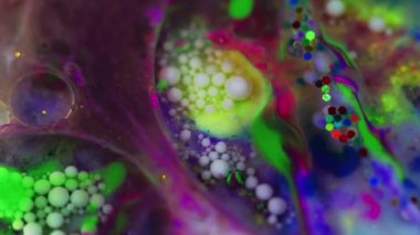 Yüzen arkaplanı boya. Mürekkep karışımı. Renkli yağ suyu. Şeffaf yuvarlak damla ile canlı pembe yeşil mavi soyut girdaplar beyaz baloncuk mor sıvı içinde yayılıyor.