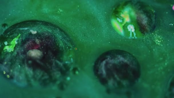摘要背景 闪闪发光的混合 神奇的液体紫色金属晶粒纹理油墨漂浮在绿色光泽物质表面的浮油圆圈 — 图库视频影像