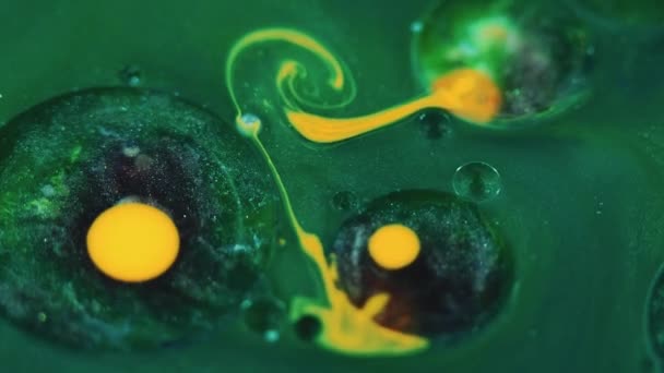 色彩斑斓的液体背景 墨水泡沫混合在一起 神秘的液体 带有黄色涡旋的油色圆形污迹在绿色闪光物质表面上的抽象运动 — 图库视频影像