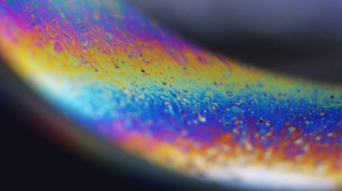 Neon boya. Holografik küre. Psikedelik rüya. Siyah soyut sanat arka planında odaksız gökkuşağı rengi yağ kabarcığı sıvı mürekkep akışı hareketi.