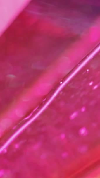 バーティカルビデオ 流動的な背景を明るくする スパークリングウェーブ グリッターゲル 抽象的な催眠術の滑らかな質の効果で広がる明るいピンクの光沢のある液体塗料の流れ — ストック動画