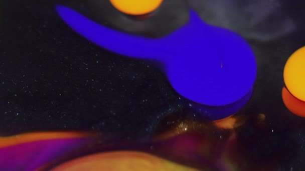 抽象的な背景 液体塗料ミックス インクアート 明るい紫色の青色のオレンジ色のこぼれは黒い光る水面の催眠運動を汚します — ストック動画