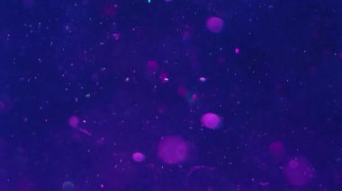 Bokeh ışıkları. Görüntü parıldıyor. Su parçacıkları akar. Işıl ışıl daireler koyu mavi menekşe sıvısı içinde yüzer okyanus illüzyonunda ışıldar soyut arka plan sanatı.